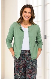 Damencardigan in salbeigrün, glatt, mit rundem Kragen, durchgehenden Knöpfen, langärmelig, getragen von lächelnder stehender Frau, offene Front, lockere Passform