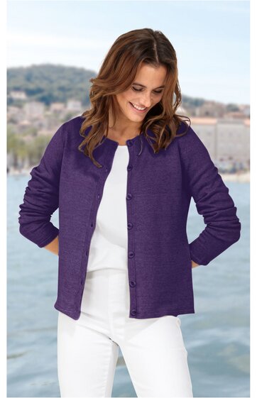 Damenjacke in dunkellila, einfarbig, mit Knöpfen vorne, Rundhalsausschnitt, lange Ärmel, gerade geschnitten, getragen von stehender Frau mit weißem Oberteil und weißer Hose