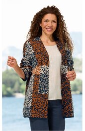 Lange Strickjacke in Braun, Dunkelblau, Beige mit abstraktem Muster, offene Front, lange Ärmel, getragen von lächelnder Frau mit lockigen Haaren, stehende Pose, helle Bluse und dunkle Hose darunter
