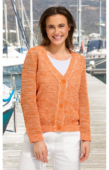 Orangefarbener Strickcardigan mit V-Ausschnitt, langen Ärmeln, Knopfleiste vorne, getragen von stehender Frau vor Hafen mit Segelbooten, locker sitzend