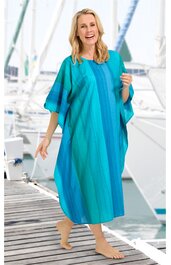 Locker geschnittenes Kaftankleid in mehreren Türkistönen mit vertikalen Streifen, mit weitem U-Boot-Ausschnitt, halblangen weiten Ärmeln, knöchellang, getragen von stehender Frau am Steg