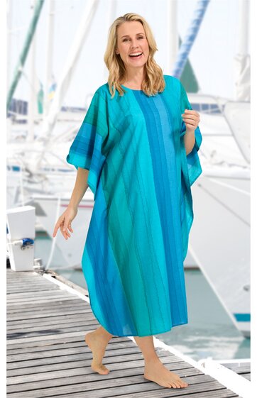 Locker geschnittenes Kaftankleid in mehreren Türkistönen mit vertikalen Streifen, mit weitem U-Boot-Ausschnitt, halblangen weiten Ärmeln, knöchellang, getragen von stehender Frau am Steg