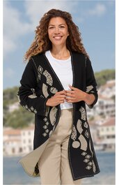 Schwarzer Cardigan mit abstraktem beigem Muster, offene Front, lange Ärmel, gerade geschnitten, getragen von stehender Frau, kombiniert mit weißem T-Shirt und beiger Hose