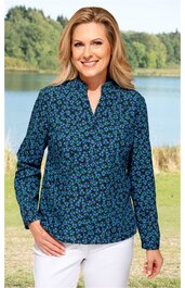 Bluse, dunkelblau mit kleinem blau-grünem Blumenmuster, Stehkragen mit Schlitz, lange Ärmel mit Knöpfen, gerade geschnitten, getragen von lächelnder stehender Frau vor See und Wald