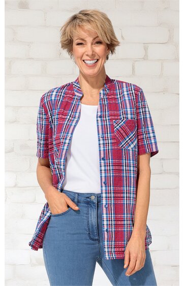 Karierte Bluse in Rot und Blau, kurzärmlig, mit Knopfleiste und Brusttasche, getragen von lächelnder Frau mit kurzem Haar, offen über weißem T-Shirt, zum Teil in blaue Jeans gesteckt