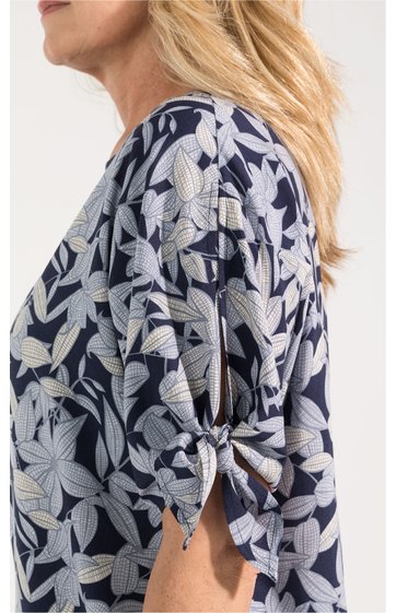 Dunkelblaues Oberteil mit großflächigem weißen Blumenmuster, kurzärmlig mit Tunnelzug und Schleife am Ärmelsaum, Rundhalsausschnitt, getragen von seitlich fotografierter Person