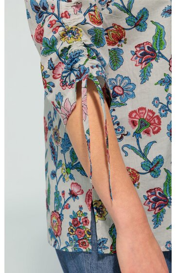Langärmliges Oberteil in Hellgrau mit buntem Blumenmuster, Ärmel mit geraffter Manschette und schmalen Bindebändern, gerade geschnitten, sichtbar Armmuskel und blaue Jeans
