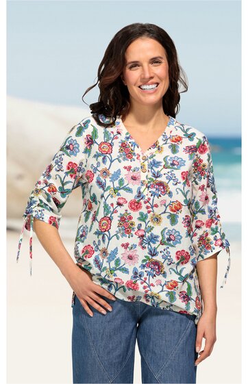 Weiße Bluse mit buntem Blumenmuster in Rot, Blau und Grün, V-Ausschnitt, halblange Ärmel mit Kordelzug, locker geschnitten, getragen von stehender Frau, casual Look