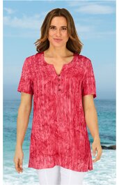 Rotes Kurzarmshirt mit unregelmäßigem Batikmuster, V-Ausschnitt mit Knopfleiste, locker geschnitten, getragen von stehender Frau vor Meereshintergrund