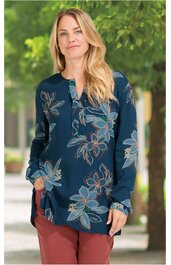 Dunkelblaues Langarmshirt mit großem Blumenmuster in Hellblau und Beige, Rundhals mit kurzem Schlitz, locker geschnitten, getragen von stehender Frau mit Händen in den Taschen