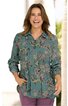 Langärmlige Bluse in grünblau mit Blumenmuster, Hemdkragen, Knopfleiste, locker geschnitten, getragen von lächelnder Frau, Hände in Taschen, kombiniert mit violetten Hosen