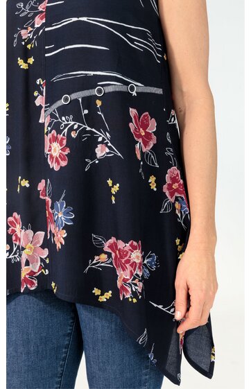 Dunkelblaues ärmelloses Damenoberteil mit mehrfarbigem Blumenmuster und weißen Linien, asymmetrischer Saum, Rundhalsausschnitt, getragen von stehender Person, locker geschnitten