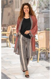 Locker sitzende Hose mit senkrechten Streifen in Beige, Braun und Schwarz, kombiniert mit schwarzem, langärmligem Oberteil und rotem, gemustertem Kimono mit grauem Rand, getragen von stehender, lächelnder Frau im Freien