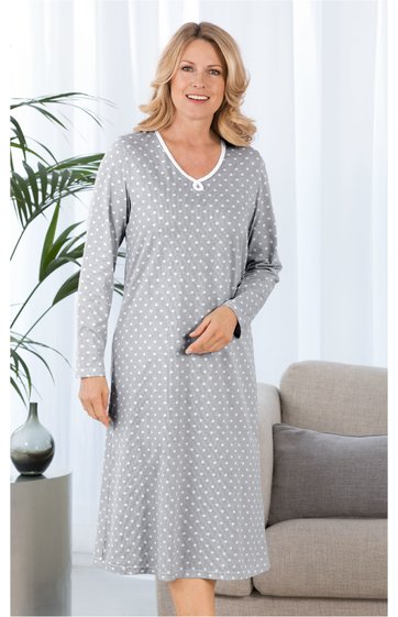 Hellgraues Nachthemd mit weißen Punkten, V-Ausschnitt mit weißem Besatz, lange Ärmel, knielang, gerade geschnitten, getragen von stehender Frau, weicher fallender Stoff