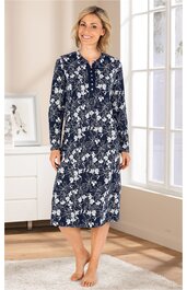 Dunkelblaues, knielanges Nachthemd mit weißem Blumenmuster, lange Ärmel, Rundhalsausschnitt mit kurzer Knopfleiste, getragen von stehender Frau in hellem Raum