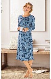 Blaues Nachthemd mit dunkelblauem Blumenmuster, lange Ärmel, rundhals, knielang, locker geschnitten, getragen von stehender Frau, die eine Tasse hält