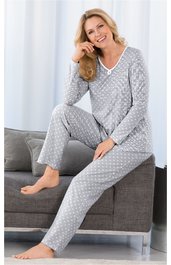 Grauer Pyjama mit weißem Punktemuster, langer Arm, V-Ausschnitt mit Knopfdetail, lange Hose, getragen von sitzender Frau auf grauem Sofa