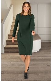 Dunkelgrünes, knielanges Kleid mit langen Ärmeln, Rundhalsausschnitt, vertikalen Nähten, schmaler Passform, getragen von einer lächelnden Frau im Stehen