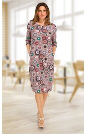 Knielanges Kleid in Altrosa mit rundem Halsausschnitt, dreiviertel Ärmeln, buntem Kreis- und Punkte-Muster, taillierter Form, seitlichen Eingrifftaschen, getragen von stehender Frau