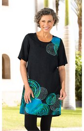 Schwarzes Freizeitkleid mit türkisfarbenen, kreisförmigen Mustern, kurze Ärmel, Rundhalsausschnitt, knielang, gerade geschnitten, getragen von stehender Frau mit lächelndem Gesichtsausdruck