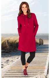 Rotes Sweatkleid mit Kapuze und Kängurutasche, langärmlig, gerade geschnitten, getragen von lächelnder stehender Frau, kombiniert mit schwarzen Leggings und roten Sportschuhen