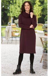 Bordeauxrotes Kleid mit Rollkragen, langärmlig, knielang, schmaler Schnitt, getragen von stehender Frau mit schwarz langen Strümpfen und schwarzen Stiefeln
