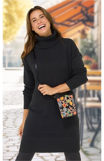 Schwarzes Rollkragen-Strickkleid mit langen Ärmeln, Rippstrick an Ärmeln und Saum, knielang, getragen von lächelnder stehender Frau, schwarze Umhängetasche mit farbigem Blumenmuster und Reißverschluss