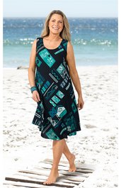 Ärmelloses, knielanges Damenkleid in Schwarz mit türkisfarbenem grafischem Muster, Rundhalsausschnitt, ausgestellter Rock, getragen von lächelnder Frau stehend am Strand