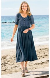 Dunkelblaues Maxikleid mit kurzem Ärmel, Spitze im Brustbereich, Rundhalsausschnitt, knöpfe vorne, fließender Rock, getragen von stehender Frau am Strand