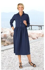 Marineblaues Hemdblusenkleid mit halblangen Ärmeln, Knopfleiste bis zur Taille, Kragen, lockerer Rock, knöchellang, getragen von stehender Frau am Strand