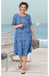 Blaues Midikleid mit weißen Blumenmustern, Rundhalsausschnitt, kurze Ärmel, locker fallend, getragen von stehender Frau, knielang