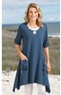 Blaues Longshirt mit weitem Schnitt, asymmetrischem Saum, Rundhalsausschnitt mit weißem Spitzeneinsatz, halbarmig, zwei aufgesetzte Taschen vorne mit Knöpfen, getragen von stehender Frau am Strand