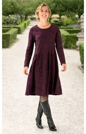 Dunkelviolettes, knielanges Kleid mit langem Arm, Rundhalsausschnitt, Kellerfalten im Rockteil, getragen von stehender Frau im Außenbereich, ausgestellter Rock, ohne Muster, kombiniert mit schwarzen Stiefeln