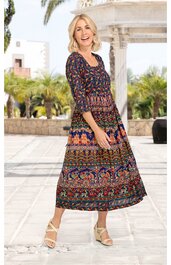 Maxikleid in dunklem Marineblau mit buntem ethnischem Muster, U-Boot-Ausschnitt, 3/4-Ärmel, tailliert mit gerafftem Bund, ausgestellter Rock, getragen von lächelnder stehender Frau mit offenem blondem Haar