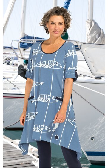 Blaues Kleid mit weißem Fischgrätenmuster, asymmetrischer Saum, kurze Ärmel, Rundhalsausschnitt, figurumspielend, getragen von stehender Frau vor Segelbooten