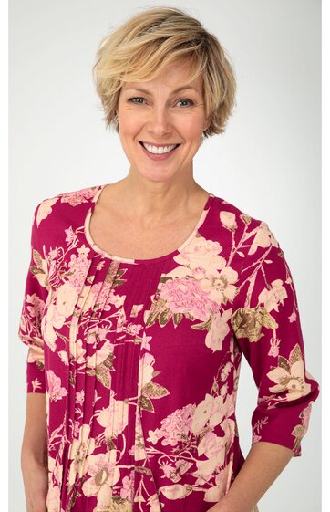 Magentafarbenes Damenoberteil mit beigem Blumenmuster, U-Ausschnitt, 3/4-Ärmel, lockere Passform, vorne Teilungsnähte, getragen von lächelnder stehender Frau