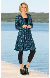 Dunkelblauer Mantel mit Blumenmuster in Hellblau und Türkis, langer Schnitt mit Kragen, Knopfleiste, getragen von stehender Frau am Steg, kombinierbar mit schwarzer Leggings und schwarzen Stiefeletten
