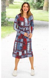 Knielanges Kleid mit langen Ärmeln, buntes geometrisches Muster in Rot, Blau, Weiß, Rundhalsausschnitt, taillierte Form, getragen von lächelnder stehender Frau im Freien, weißleuchtende Sneakers