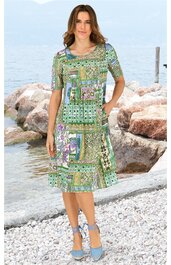 Knielanges Kleid in Grün mit geometrischem und floralem Muster, Rundhalsausschnitt, kurze Ärmel, gerade geschnitten, getragen von stehender Frau, leicht elastisch