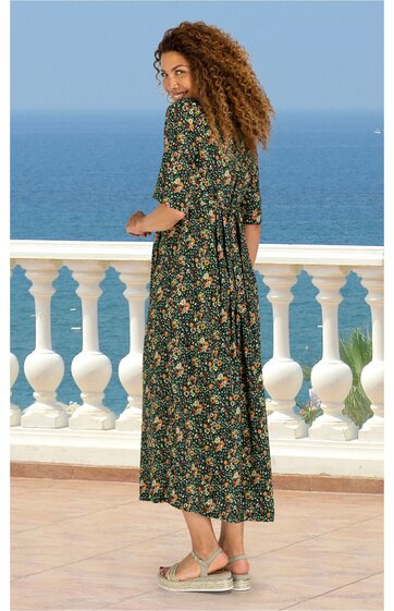 Maxikleid dunkelgrün mit Blumenmuster, halbärmel, runder Halsausschnitt, geraffte Taille mit Bindegürtel, weite ausgestellte Form, getragen von stehender Frau, Rückenansicht, Sandalenfarbe beige