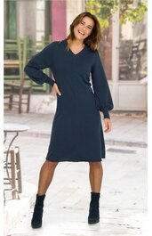 Dunkelblaues Kleid mit V-Ausschnitt, langen Ballonärmeln, knielang, ohne Muster, getragen von lächelnder stehender Frau, gerade geschnitten