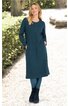 Dunkelgrünes Midikleid, lange Ärmel, Rundhalsausschnitt, seitliche Taschen, gerade geschnitten, getragen von stehender Frau mit verschränkten Armen