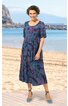 Knielanges Kleid in Dunkelblau mit roten und hellblauen Blumenmustern, halblange Ärmel, Rundhalsausschnitt, taillierte Form getragen von einer lächelnden Frau am Strand, mit hellblauen Sandalen
