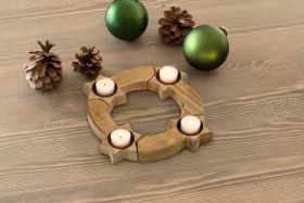 Holz-Teelichthalter in Sternform mit vier brennenden Teelichtern auf Holztisch, umgeben von zwei grünen Weihnachtskugeln und drei Kiefernzapfen, Weihnachtsdekoration