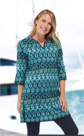 Frau trägt blau-grünes Baumwoll-Kleid mit abstraktem Muster, V-Ausschnitt und 3/4-Ärmeln, steht vor verschwommenem Hintergrund mit Booten und Wasser, lächelt freundlich