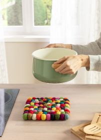 bunte quadratische Filz-Untersetzer mit runden Kugeln auf einer Küchenarbeitsplatte, grün-weißer Topf mit Holzgriffen wird gerade darauf abgestellt, helle Küche mit Fenster im Hintergrund