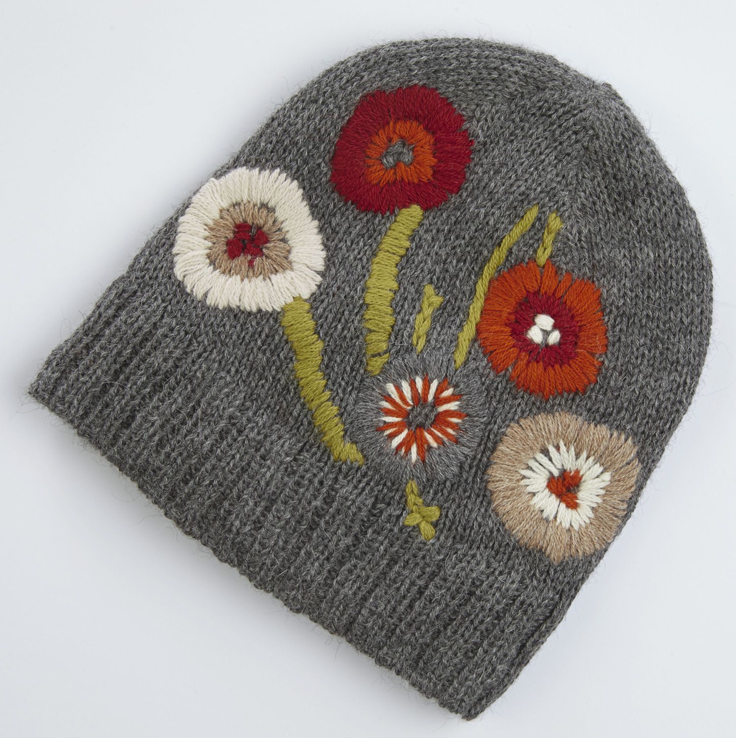 Grau gestrickte Alpaka-Mütze mit bunter, gestickter Blumenverzierung in Rot, Orange, Weiß und Beige, grüne Stängel und Blätter, grobe Strickstruktur, warme Winterkopfbedeckung