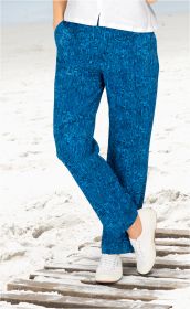Damen Viskose-Hose in Blau mit abstraktem Muster, gerade geschnitten, getragen mit weißer Bluse und weißen Sneakern, stehend auf Holzplanken im Sand