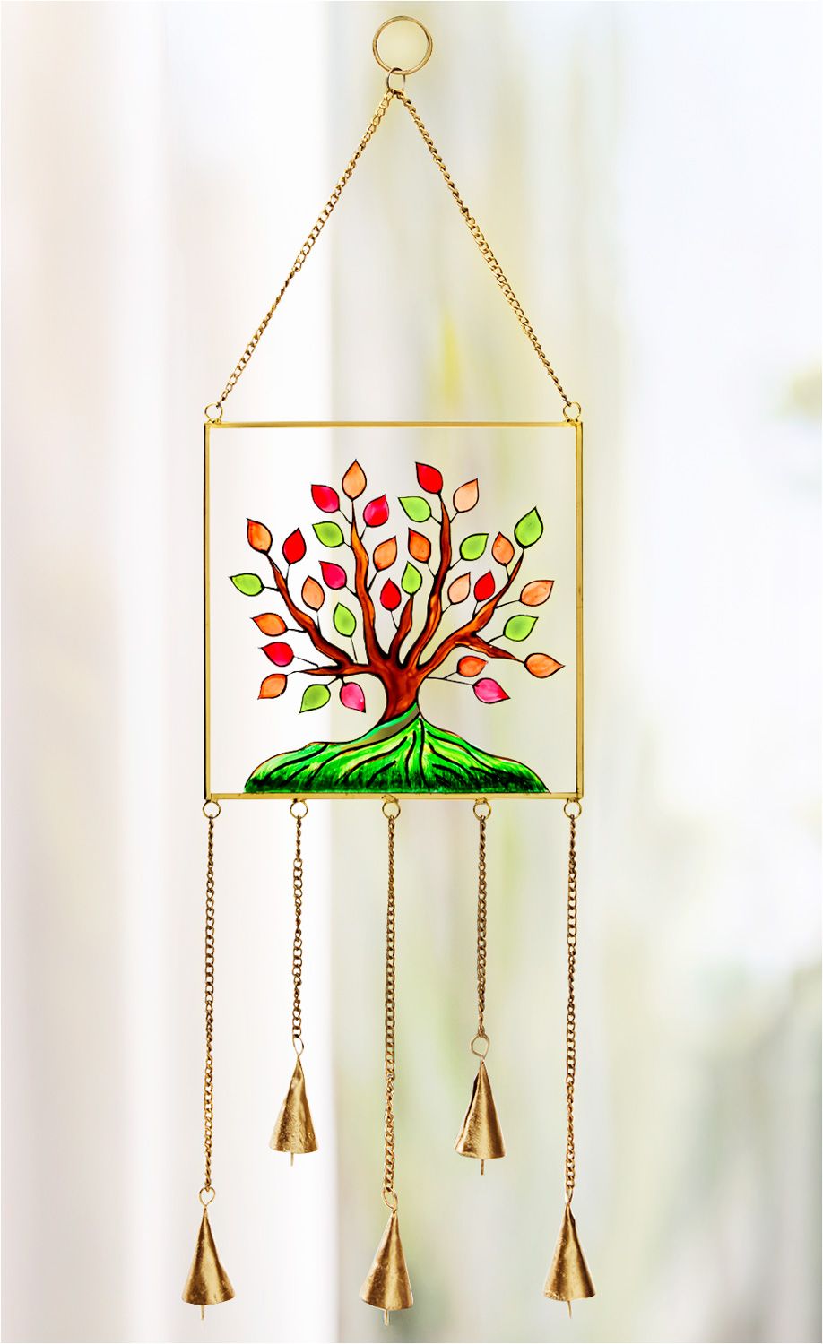 Fensterbild mit farbigem Baum-Motiv in Rot, Orange und Grün, Rahmen und Ketten in Gold, fünf Glocken hängen an goldenen Ketten unten, helles unscharfes Hintergrundlicht