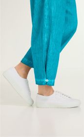 Unterschenkel einer Person, die eine türkisfarbene Viskose-Mix Hose mit Knopf am Beinabschluss und weiße Sneaker trägt, auf hellem Hintergrund stehend